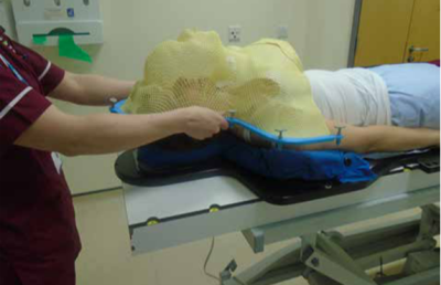 The patient is lying on a trolley and wearing the mask, ready for treatment