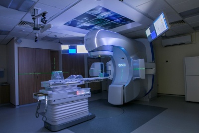 The stereotactic radiosurgery treatment machine is a large machine with a table for patients to lie on. A large arm rotates around the bed to deliver the treatment